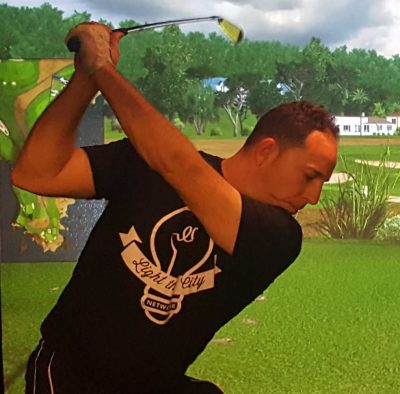 Jason Pickett swinging a golf club at a golf simulator